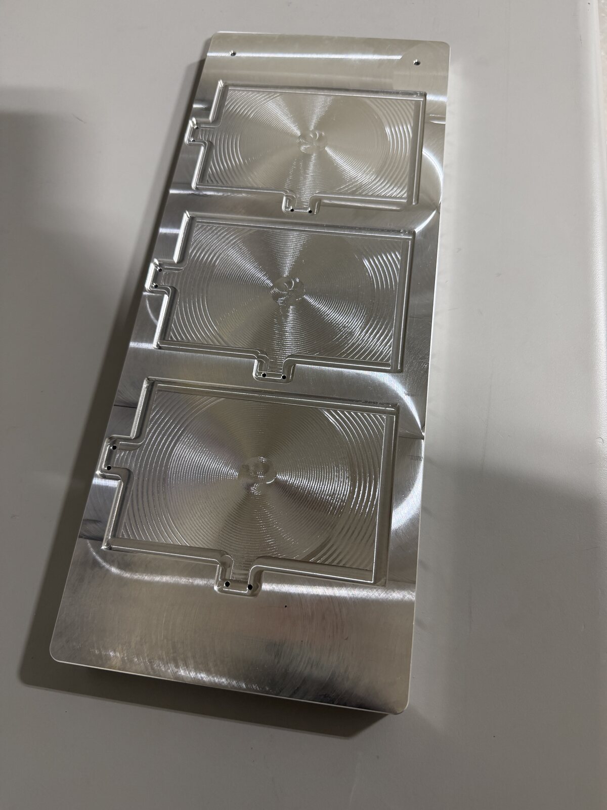 Machined aluminum fixture plate with three repeated recessed pockets